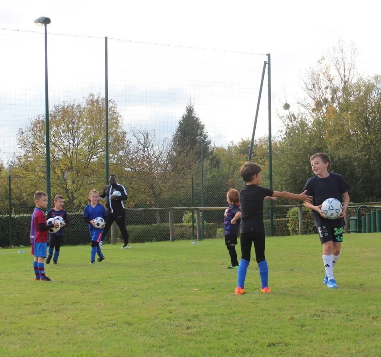 Jeunes en activité avec des ballons sur un terrain de football