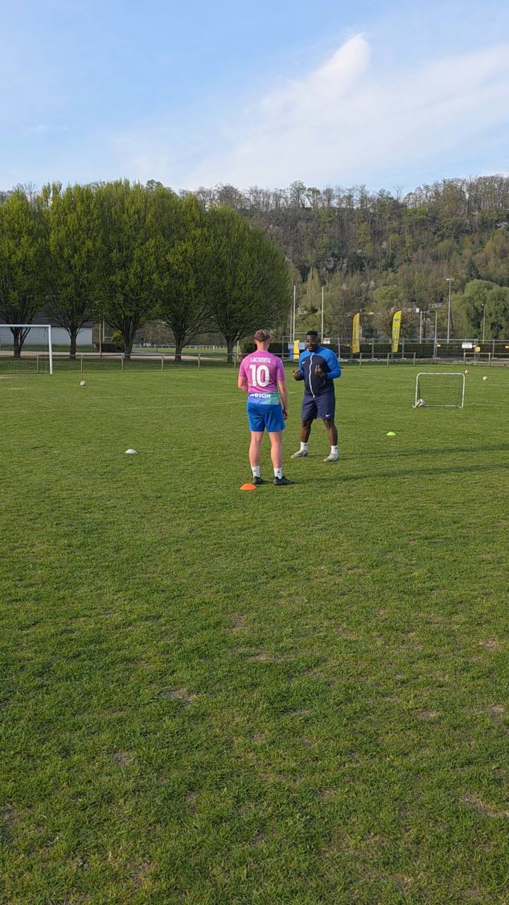 Coach La Win échange individuellement avec un joueur sur un terrain de football